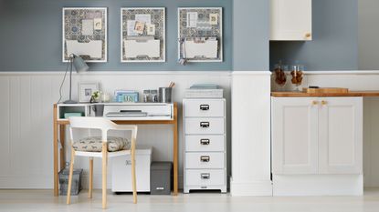 Blue and white home office with three matching pinboards and a filing cabinet and laptop