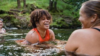 woman wearing an orange swimming costume a river laughing with her friends