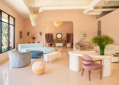 A rosewater-tinted design showroom filled with furniture.