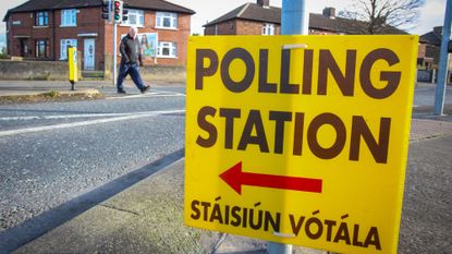 Pedestrian walks past Polling Station signs in Cabra, Dublin