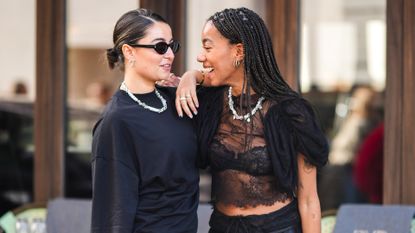 Two guests in black with bright glowy skin talking and laughing