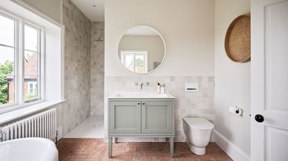 White bathroom with round mirror and green vanity