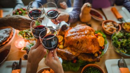 A stock photo of people toasting at a Thanksgiving dinner table.