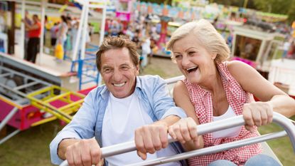 An older couple hold on while riding a roller coaster.