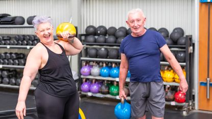 Two seniors in a gym holding kettlebells