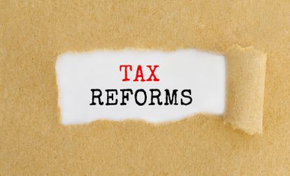 the words tax reforms showing through a torn piece of paper