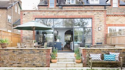 Brick extension with flat roof and fixed glazing leading out to patio and garden