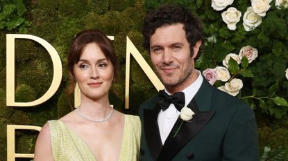 Leighton Meester wearing a lime gown and Adam Brody wearing a green tux posing in front of a flower wall at 2025 Golden Globes