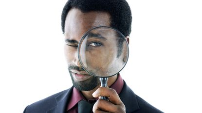 A man holds a magnifying glass up to his eye.