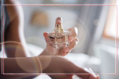 A close up of a woman spraying perfume on her wrist