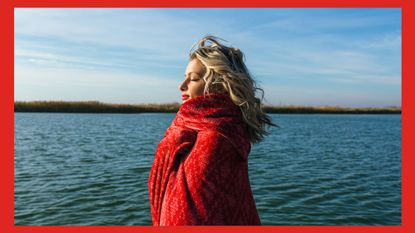 Portrait of woman by a lake wrapped in a red blanket