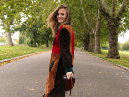 Fashion editor Emma Spedding wearing Rixo patchwork suede fall coat in park. 