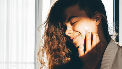 A woman applying moisturiser to her face