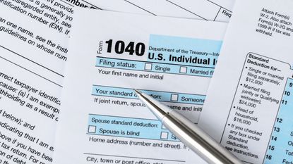 A silver pen sits atop spread-out tax forms.