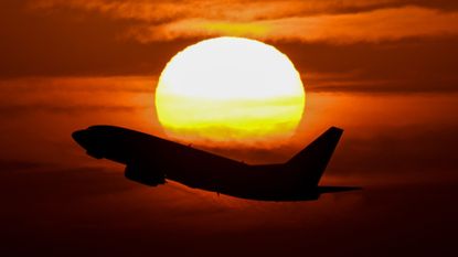 A plane takes off in Buenos Aires amid a looming sunrise