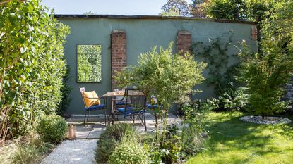 Garden with lawn, gravel path, patio and painted wall