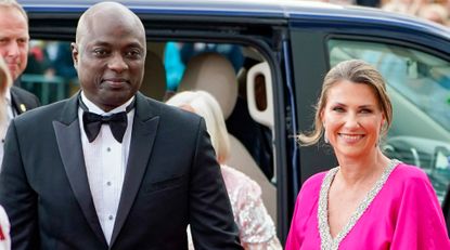 Shaman Durek wears a tuxedo as he holds hands with wife Princess Martha Louise of Norway, who wears a cerise pink gown