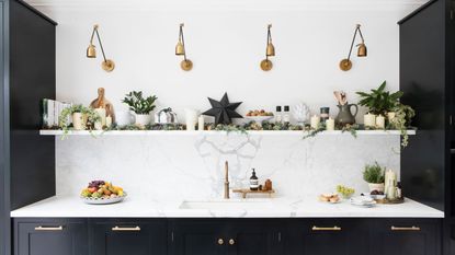 White kitchen with marble worktops and splashback, with black kitchen cupboards and gold hardware