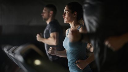 Female athlete running on treadmill during sports training in a health club.