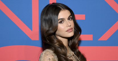 kaia gerber on a red carpet with loose waves and a sparkly cape