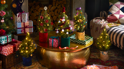 five mini christmas trees on gold table in festive living room