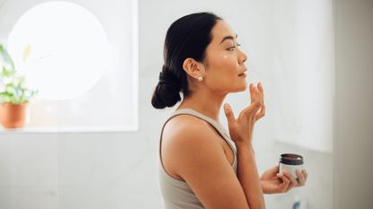 Woman applying cream to face 