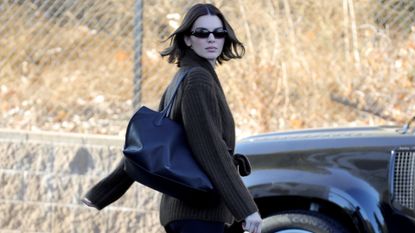 Kendall Jenner walks to her car in a brown sweater with sunglasses and a black tote by the Row