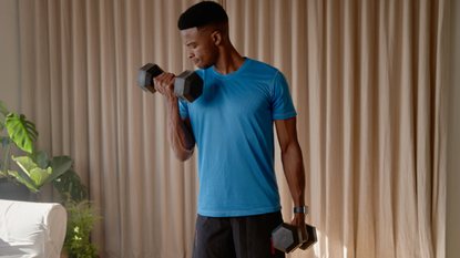 Man doing bicep curls with dumbbells in his living room