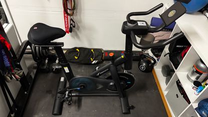 Black exercise bike surrounded by home gym equipment, including a kettlebell, sandbag and resistance bands