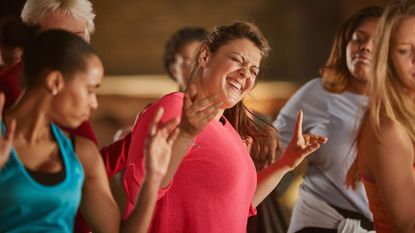 Woman laughing with others in a new beginner step aerobics class