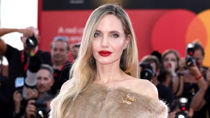 Angelina Jolie wears a fur off-the-shoulder shawl coat on the red carpet