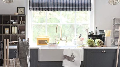 Kitchen sink in front of a window, surrounded by lots of cleaning products on the worktops 