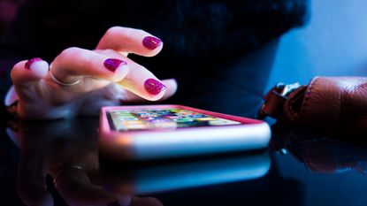 Best cheap smartphone: Pink phone on table being used by woman with pink nail polish