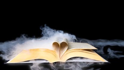 Open book with smoking effect flowing over the pages and through a heart shape made from the pages on a black background