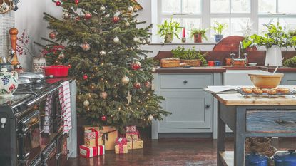 A kitchen decorated for Christmas with a large tree in the corner