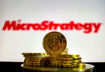 Illustration of bitcoin coins with red MicroStrategy logo blurred in the background