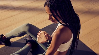 best massage gun: pictured here, a young woman using the Theragun mini Gen 2 on her arm