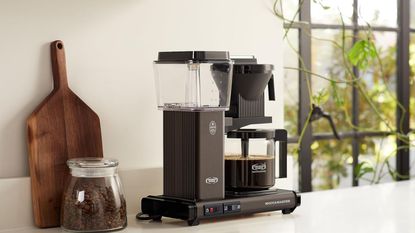 One of the best non-toxic coffee makers: The Moccamaster KGBV Select on a countertop with a wooden board and coffee canister beside it