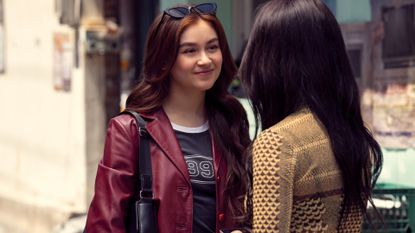 kitty wears a red leather jacket while talking to a friend on the streets of seoul in xo kitty season 2