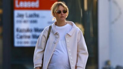 Jennifer Lawrence walks in Los Angeles wearing a pink button up coat with a white t shirt brown bag and The Row shoes