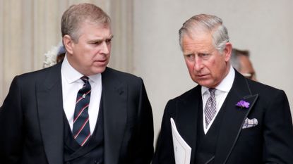 King Charles standing next to Prince Andrew, both in dark suits and serious expressions