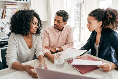 A middle-aged couple meets with a lawyer or financial planner at a table.