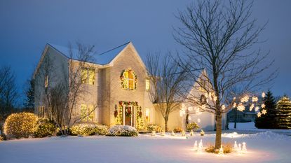 Christmas Decorated Home With Holiday Lighting in Winter with Front Yard Covered in Snow