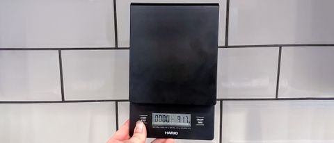 a black drip coffee scale by hario v60 is photographed against a white backsplash