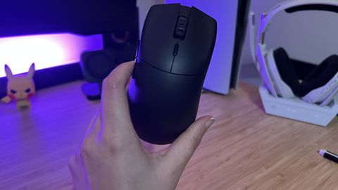 Hand holding Glorious Series 2 Pro gaming mouse against a desk setup