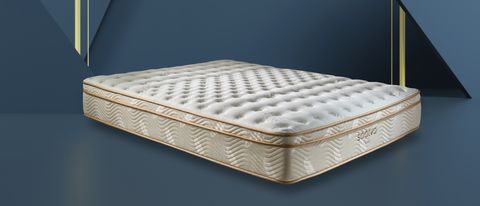 The Saatva Classic mattress photographed in our sleep studio during the testing and review process, with the cream and gold mattress shown on a deep blue-green background and with a Tom&#039;s Guide Editor&#039;s Choice 5-star rated review badge overlaid on the bottom right hand corner