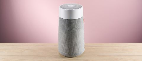 The large Blueair air purifier sits facing forward on a wood surface against a pink background.