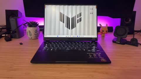 Asus TUF A14 gaming laptop on a wooden gaming desk with purple lighting