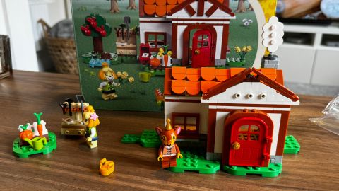 Lego Isabelle&#039;s House Visit set, box, and minifigures on a wooden table