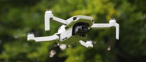 DJI Mini 4K beginner drone in flight with soft-focus foliage in the background